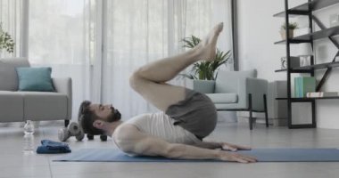 Evdeki egzersiz paspasında çalışan bir adam.