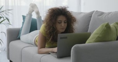 kadın kanepede yatan ve onu laptop kullanma