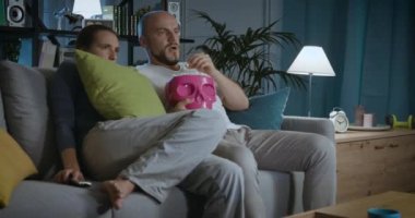 Televizyonda korku filmi izleyen bir çift.