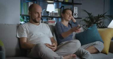 Çift evde televizyon izliyor ve uzaktan kumanda için kavga ediyor.