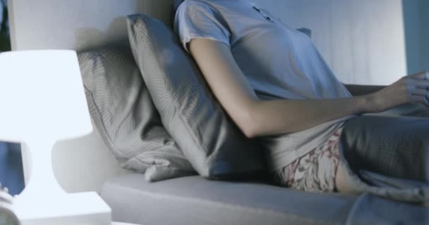 Kvinnan sitter i sängen och arbetar med sin bärbara dator — Stockvideo