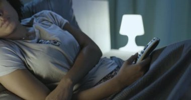 Yatakta televizyon açık bir kadın.