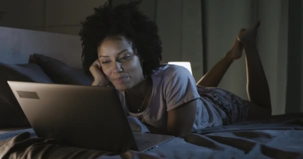 Femme afro-américaine couchée au lit et se connectant à son smartphone — Video