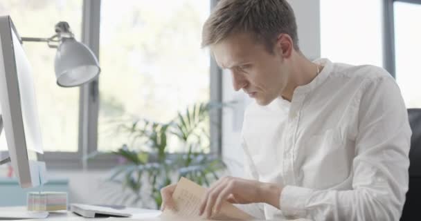 Geschäftsmann sitzt am Schreibtisch und liest Zeitung — Stockvideo