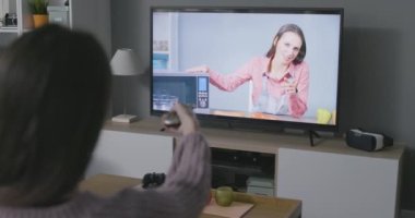 Televizyonda yemek programı izleyen bir kadın.
