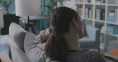 Televizyonda dikiş dersleri izleyen bir kadın.