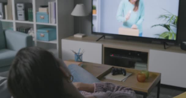 Woman watching an unboxing video on her television — Stock Video
