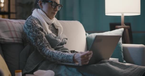 Soğuk algınlığı olan bir kadın laptopuyla bağlantı kuruyor. — Stok video