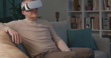 Adam kanepede oturuyor ve VR 'ın tadını çıkarıyor.