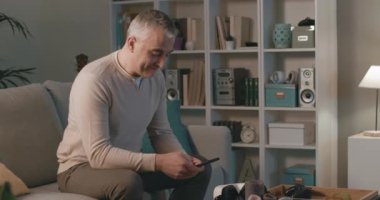 Adam kanepede oturup akıllı telefonuyla sohbet ediyor.