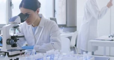 Klinik laboratuvarında mikroskop kullanan bir araştırmacı.