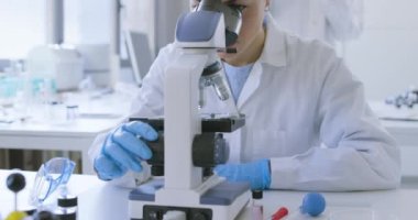 Klinik laboratuvarında mikroskop kullanan bir araştırmacı.