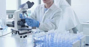 Klinik laboratuvarında mikroskop kullanan bir araştırmacı.