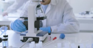 Klinik laboratuvarında mikroskop kullanan bir araştırmacı.