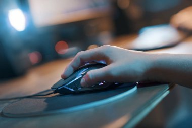 Young gamer hand on the mouse, he is playing online video games