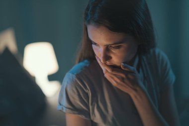 Pensive woman in her bedroom at night, she is unable to sleep