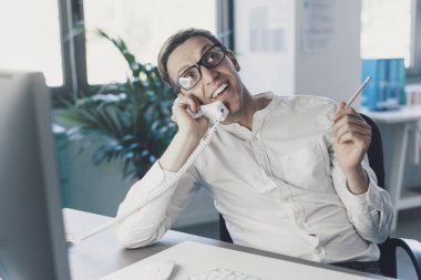 Corporate businessman sitting at desk and answering phone calls