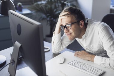 Panicked businessman sitting at desk and staring at the computer screen, system failure and computer problem concept