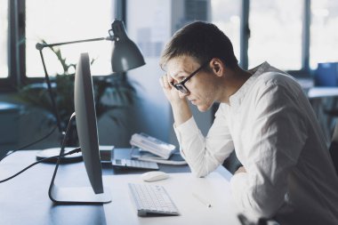 Office worker with eyesight problem, he is trying to focus on the computer screen