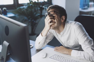 Stressed businessman sitting at desk, he is having issues with his work