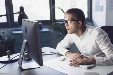 Panicked businessman sitting at desk and staring at the computer screen, system failure and computer problem concept