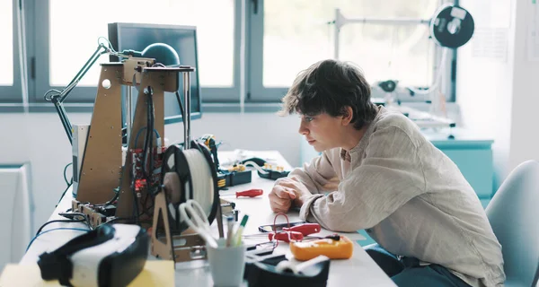 Young engineering student using a 3D printer in the lab