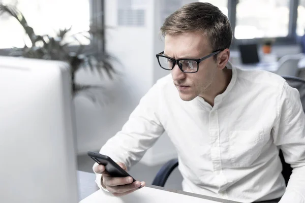 Serious Confused Businessman Sitting Desk Connecting His Smartphone — Fotografia de Stock