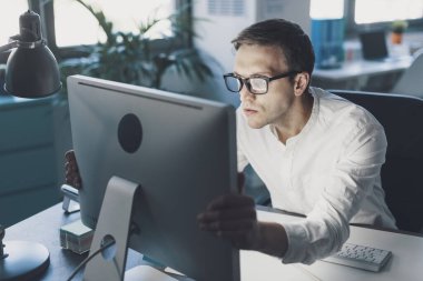 Panicked businessman sitting at desk and staring at the computer screen, system failure and computer problem concept
