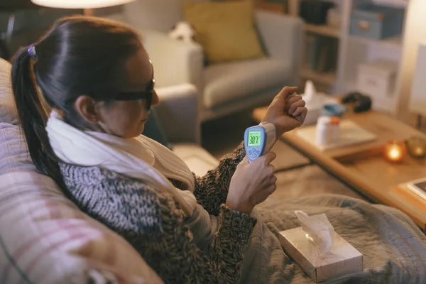 Sick Woman Resting Couch Home Measuring Her Temperature Infrared Thermometer — ストック写真