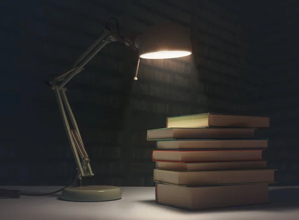 Pile of books on a desk in a library and desk lamp