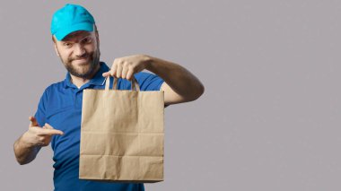 Smiling delivery guy holding a bag with a ready meal, fast food delivery concept
