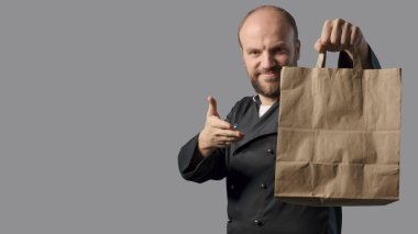 Smiling chef showing a bag with ready meal, take away food concept