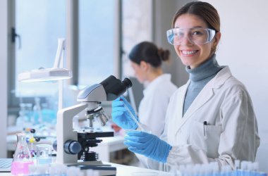 Young female student in the research lab, she is smiling and looking at camera