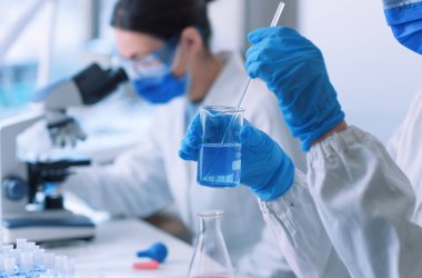 Medical research in a laboratory, a scientist is holding a beaker and mixing a liquid sample