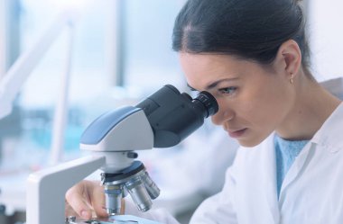 Students working in the clinical laboratory, a researcher is using a microscope in the foreground, scientific research concept