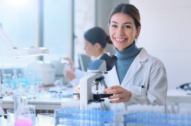 Young medical student doing research in the clinical lab, she is smiling and looking at camera