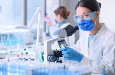 Young researcher wearing a face mask and working in a medical laboratory, she is looking at camera