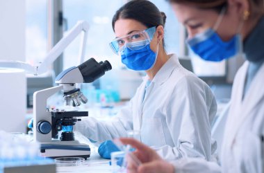 Young researcher wearing a face mask and working in a medical laboratory, she is looking at camera