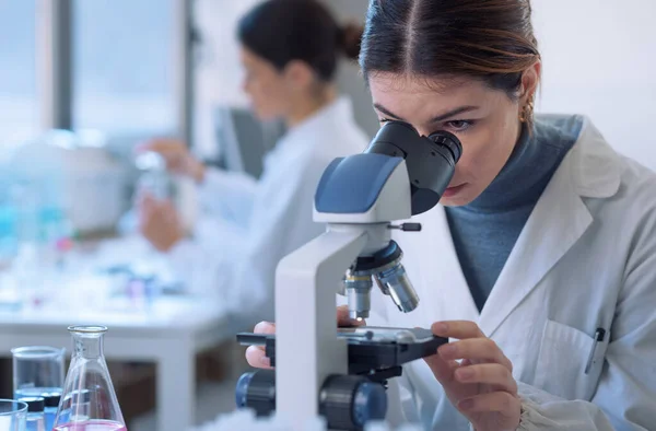 Students doing research in the clinical laboratory, a researcher is using a microscope in the foreground