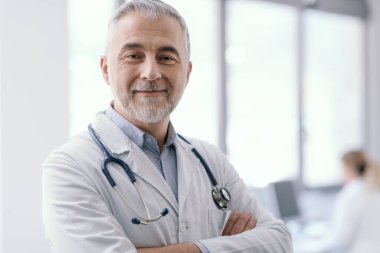 Confident doctor posing with arms crossed and smiling, healthcare and medicine concept