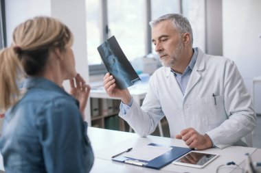 Professional doctor sitting at desk and checking a patient's radiography, she is sitting and waiting