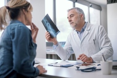 Professional doctor sitting at desk and checking a patient's radiography, she is sitting and waiting