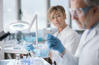 Research team working in the lab, a woman is holding test tubes and checking samples