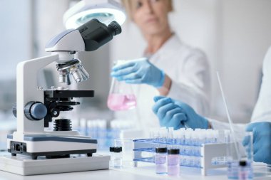 Medical researcher working in the lab, she is holding a beaker