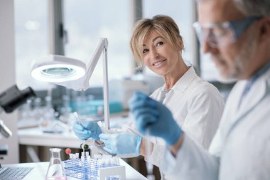 Research team working in the lab, a woman is holding test tubes and checking samples