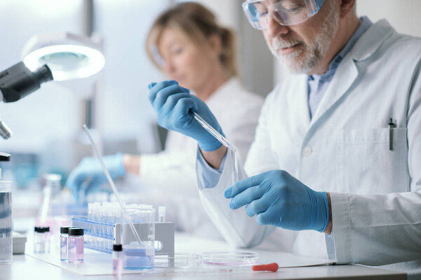 Professional medical researcher working in the laboratory, he is examining samples