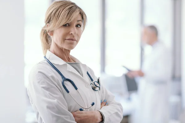 Γυναίκα Γιατρός Αυτοπεποίθηση Ποζάρει Σταυρωμένα Χέρια Γραφείο Και Ιατρικό Προσωπικό — Φωτογραφία Αρχείου