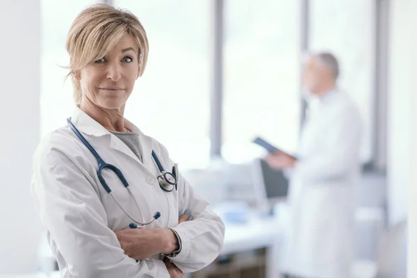 Confident Female Doctor Posing Arms Crossed Office Medical Staff Background — 图库照片