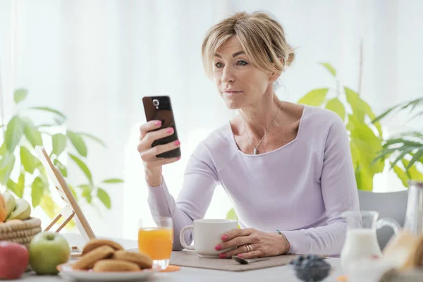 Mature Woman Having Breakfast Connecting Her Smartphone Home — Foto de Stock