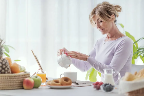Mature Woman Having Breakfast Home She Sitting Pouring Tea Cup — Foto de Stock